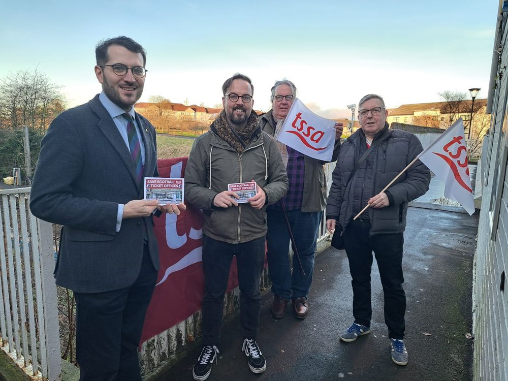 A picture of four people with leaflets in front of a TSSA banner on a railway bridge, Paul Sweeney, an MSP for Glasgow, stands on the left.  