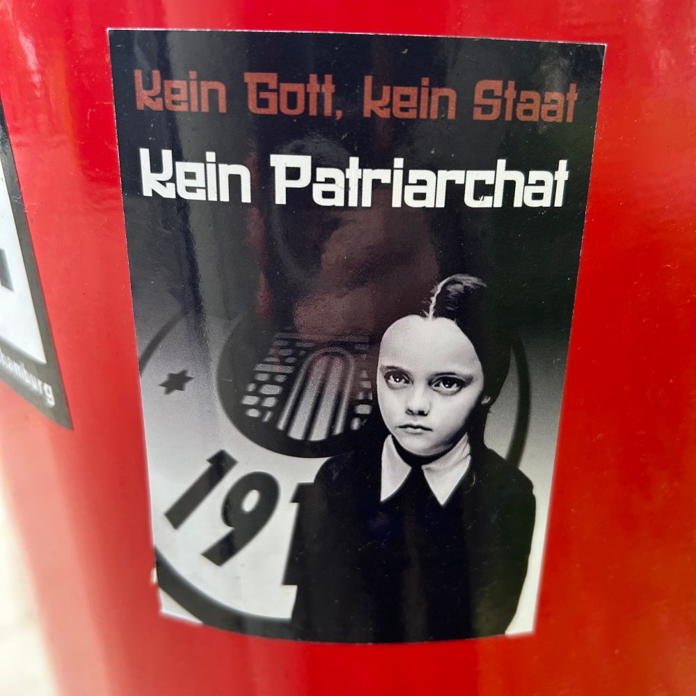 FCSP sticker reading NO GOD, NO STATE, NO PATRIARCHY, ft. Christina Ricci’s Wednesday Addams 