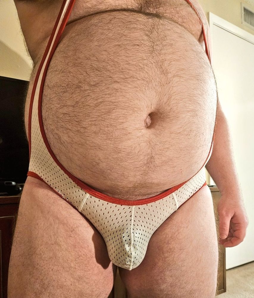 Vryk is wearing a low cut singlet. His cage is visible through the mesh