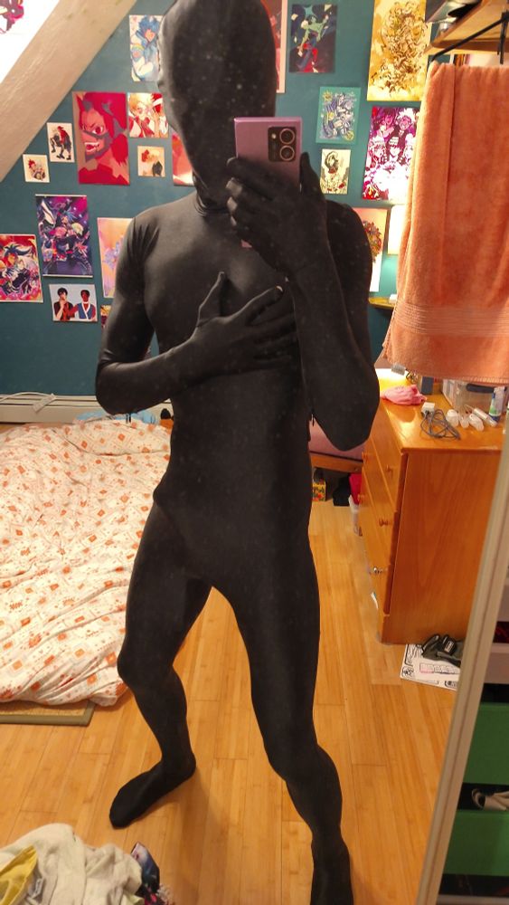 Facing a wall-length mirror wearing my custom sized black zentai suit. In a sort of athletic stance, trying to look slightly buffer than I actually am😹