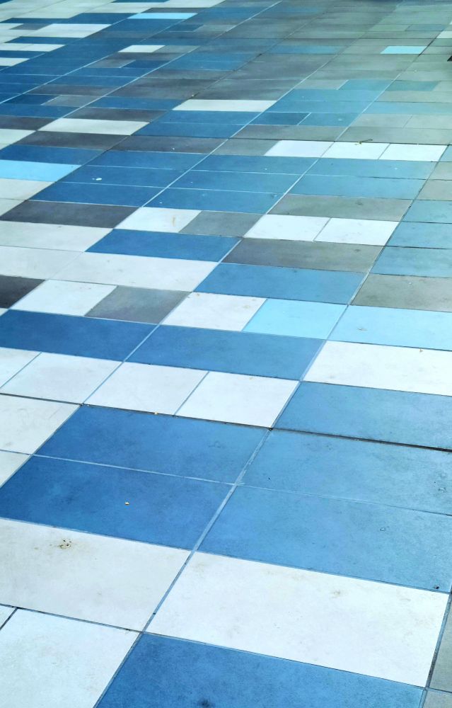 Floor/ ground tiles comprised of various shades of blue and white. 
