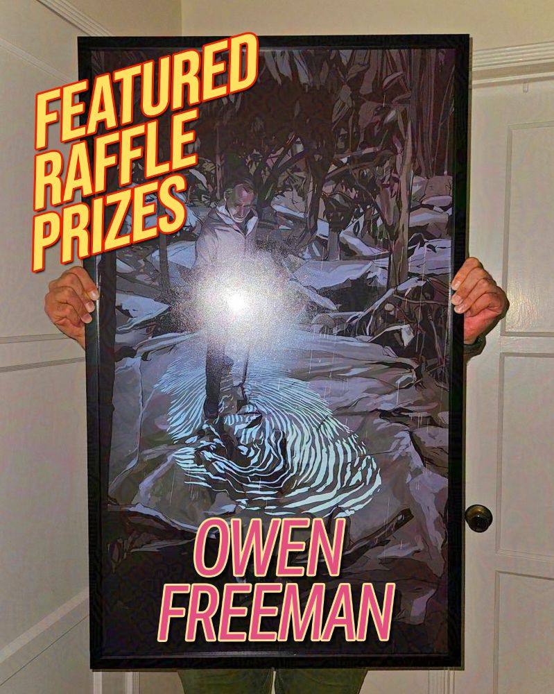 Artist Owen Freeman holding a large framed print. 