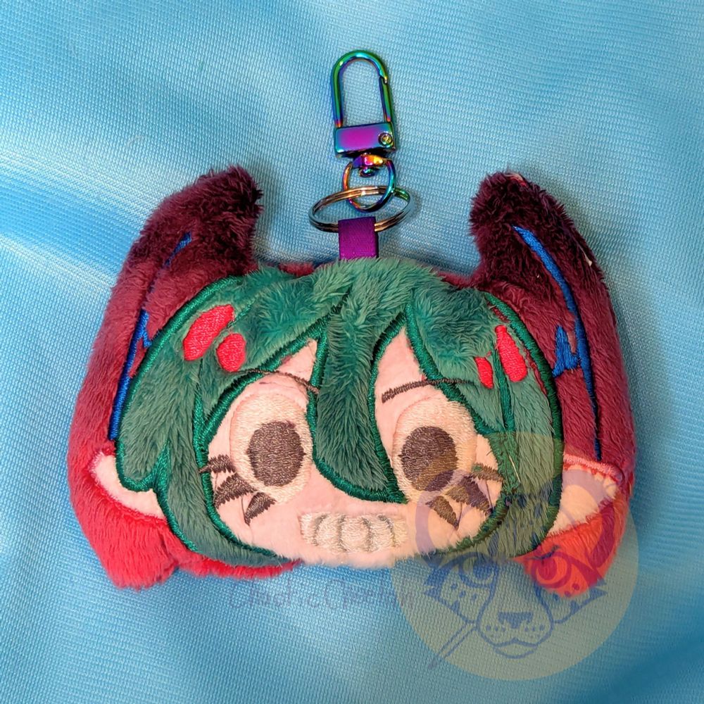Artfight attack for actuallyrea. Pink elf character with green hair and red wings. It’s a plush charm!