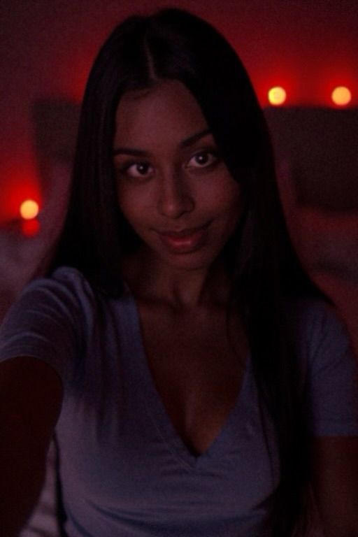 Me, in my blurred bedroom with red led lights on, wearing a light blue tshirt, while I tilt my head to the camera~