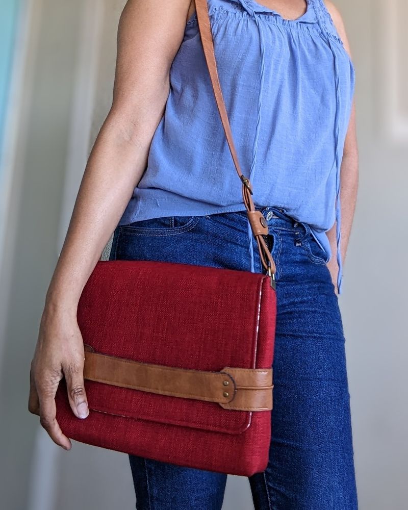 Handbag with an adjustable shoulder strap made from a deep red woven fabric and dark honey colored faux leather.