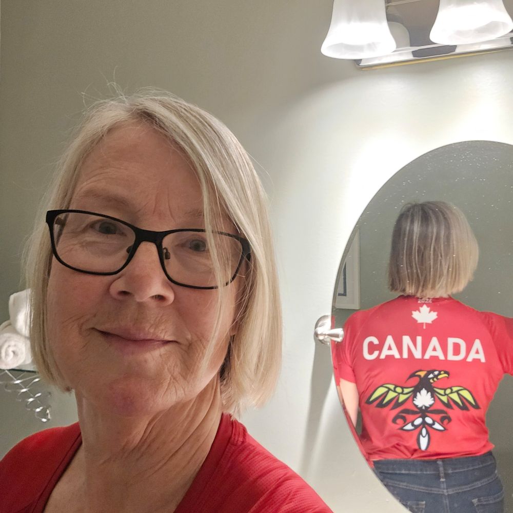 A woman wearing a red sports tee that says CANADA above an Indigenous design of a thunderbird. 
