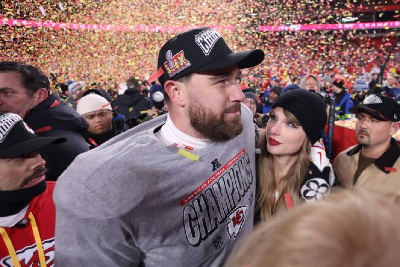 taylor and travis standing closing. taylor looking longingly at travis 