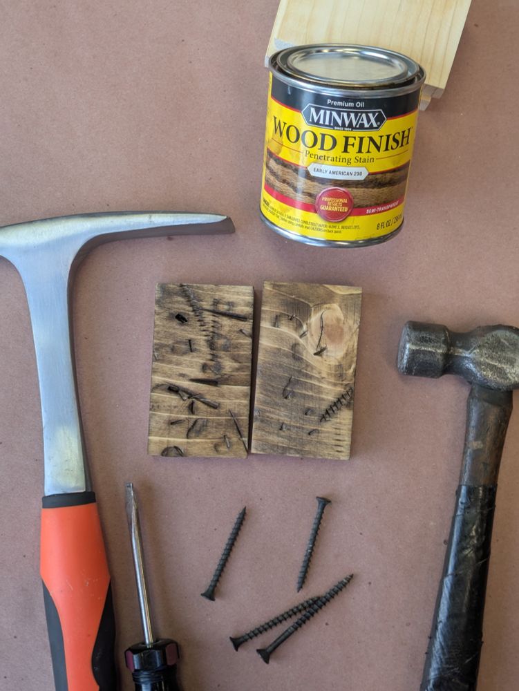 Beaten wood samples surrounded by tools and drywall screws along with one can of wood stain 