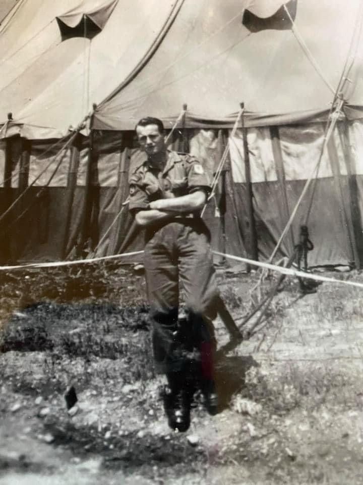 A picture of a soldier standing in front of a tent.