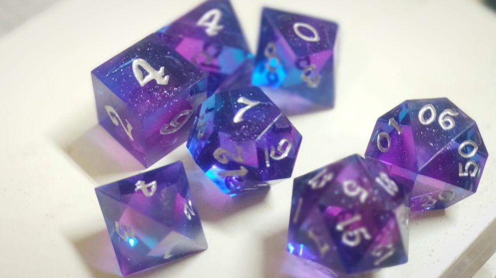 Es la foto de los dados más bonitos del mundo, con colores iriscentes entre azul y rosa , que varían con el ángulo de la luz , los números son plateados y tienen motitas de polvo de plata en su interior.