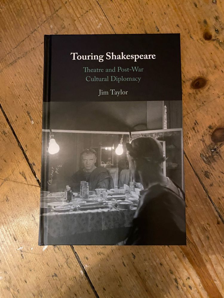 A hardback monograph, featuring an actor dressed as Julius Caesar staring into a dressing room mirror. The background is a wooden floor. 