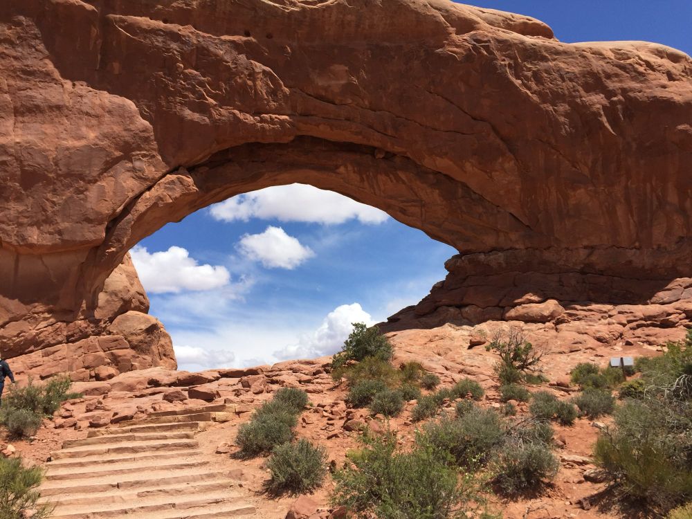 Window formation with clouds seen through it stairs, leading up to it at arches national Park