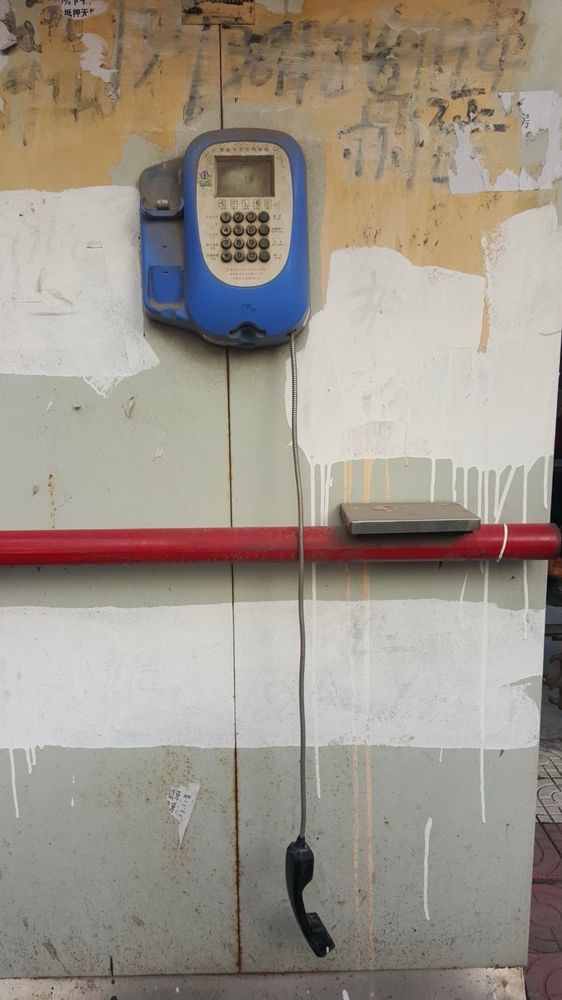Ein blaues wandtelefonhörer hàngt unter. Wand ist beschmiert mit Farbe und tec. 
