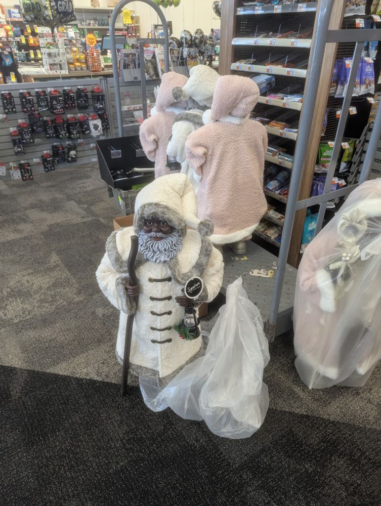 An assortment of large (approx. 3 foot tall) Santa Claus figures are being unwrapped and placed on the sales floor of a CVS.
