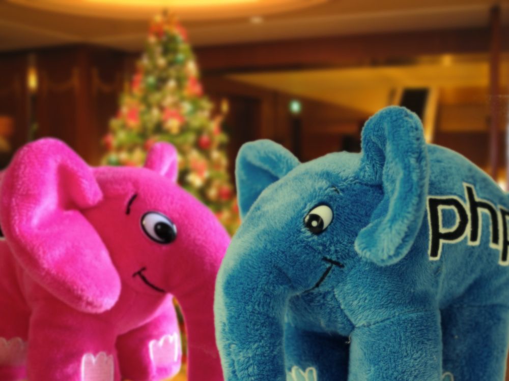 Image of two Elephpants plush toys and a Christmas tree in the back inside a cosy room.