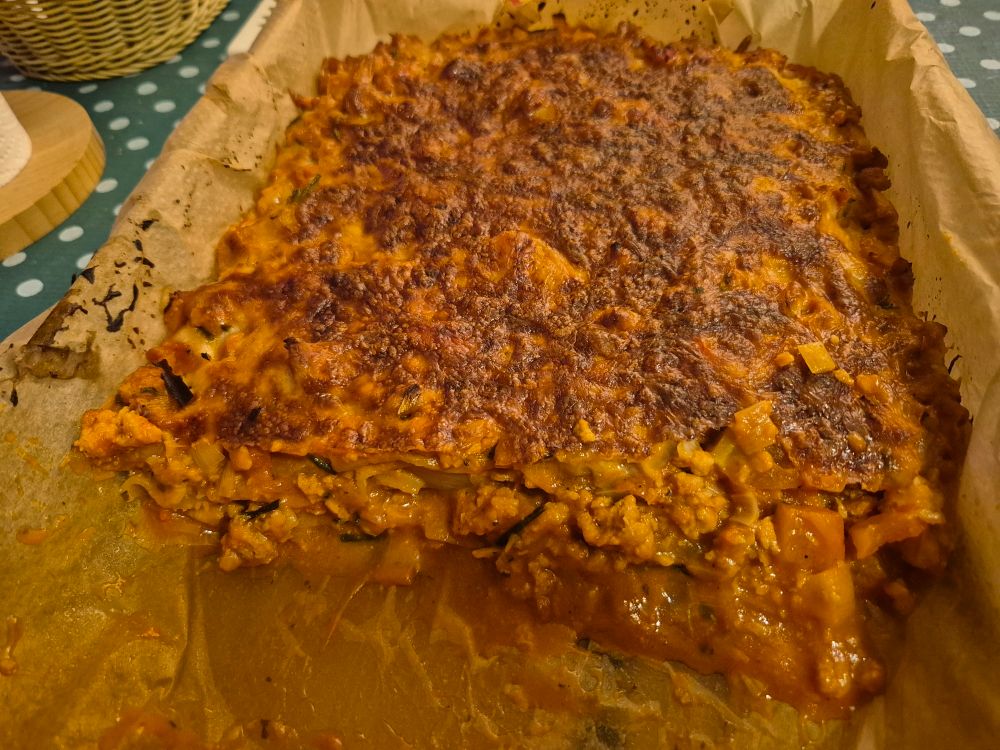 Lasaña vegetariana con un trozo quitado así que se ve el interior.