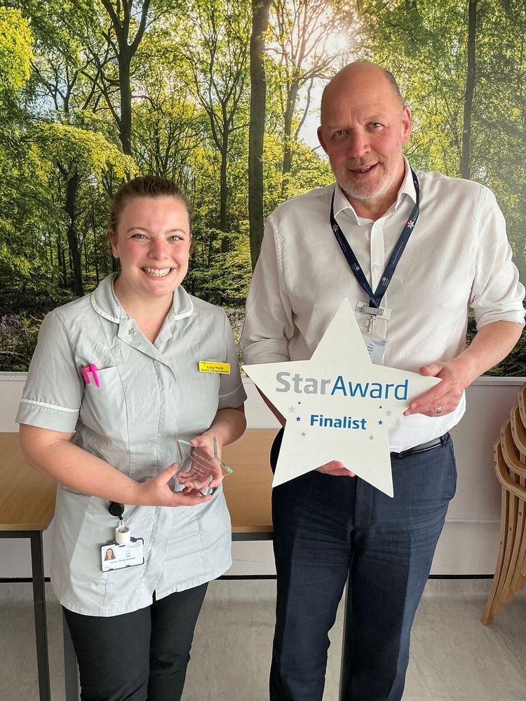 Lucy holding her Star Award trophy, standing alongside Trust Chief Executive, Simon Morritt.