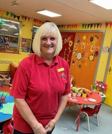 Tracey smiling in the playroom, which is brightly decorated and filled with toys.