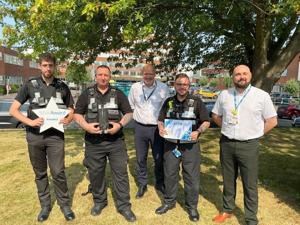 4 colleagues from the security team, standing alongside Trust Chief Executive Simon, on the grass at the front of York Hospital. 