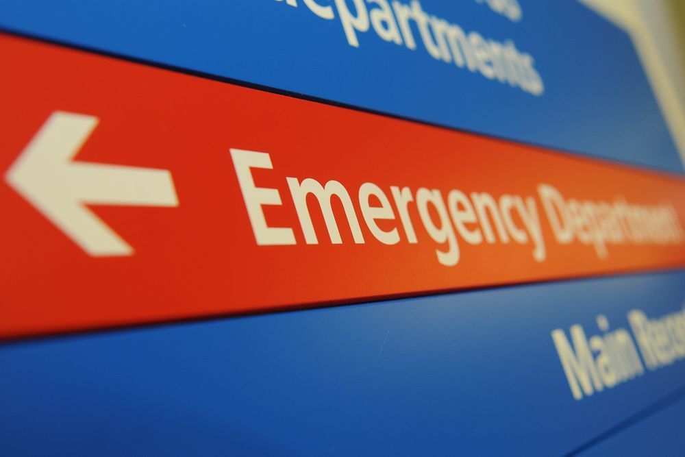 Wall sign pointing towards an emergency department.