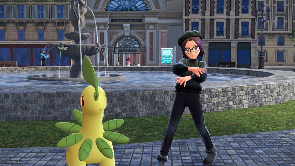 A picture from Legends: Za with my main character and Bayleef. They are posed in front of a fountain. My character is wearing a green beret, green and blue turtleneck, green glasses, black skinny jeans, and black fluffy boots. He is hitting a dance pose.