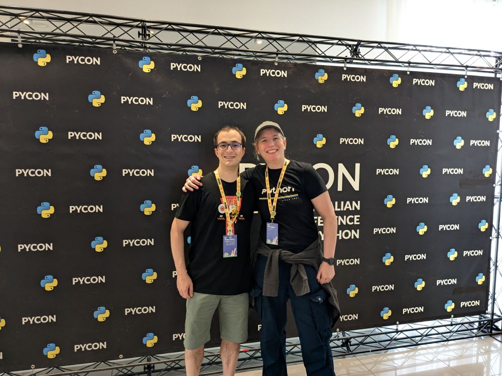 Me and Jacopo are posing in front of the photo wall at PyCon. We are both smiling.