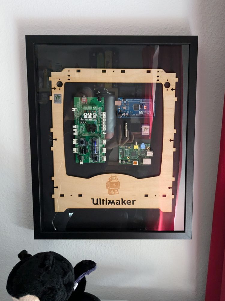 The mentioned parts of the printer mounted inside a black frame, on a black card board background.