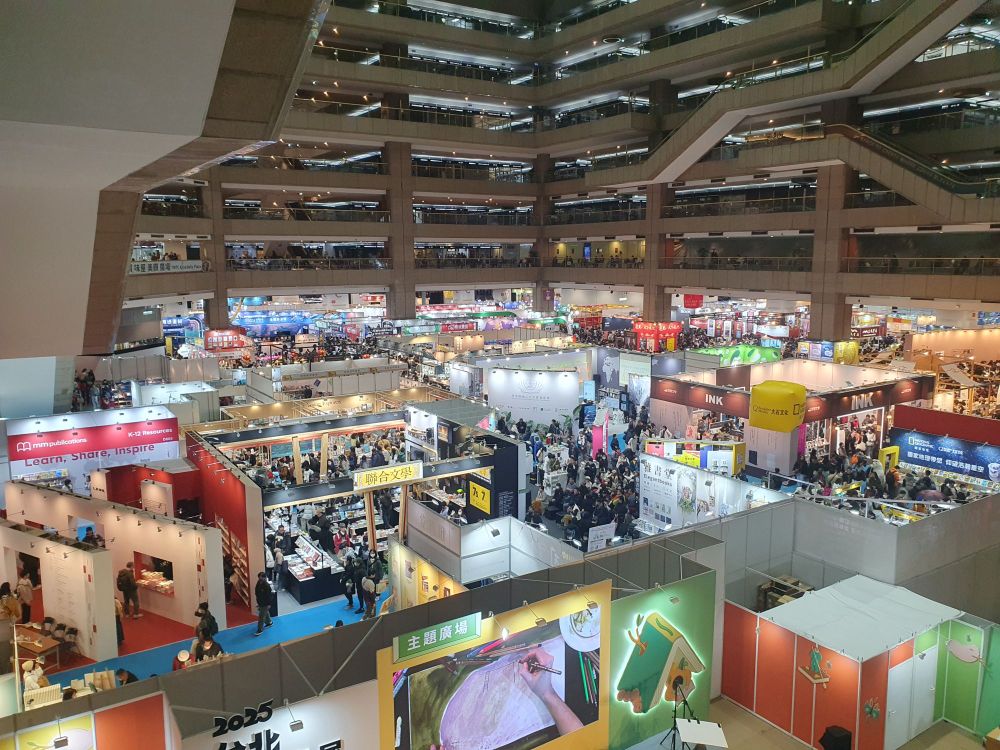 Foto van de hal waarin de boekenbeurs van Taipei wordt gehouden. Je kijkt er van bovenaf schuin op: een enorm doolhof aan standjes, met daartussen een grote menigte mensen.