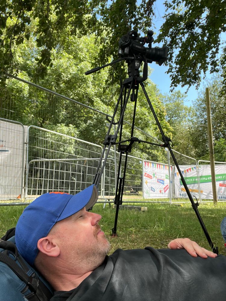 A hard working man lying down and concentrating next to his camera, but only very briefly