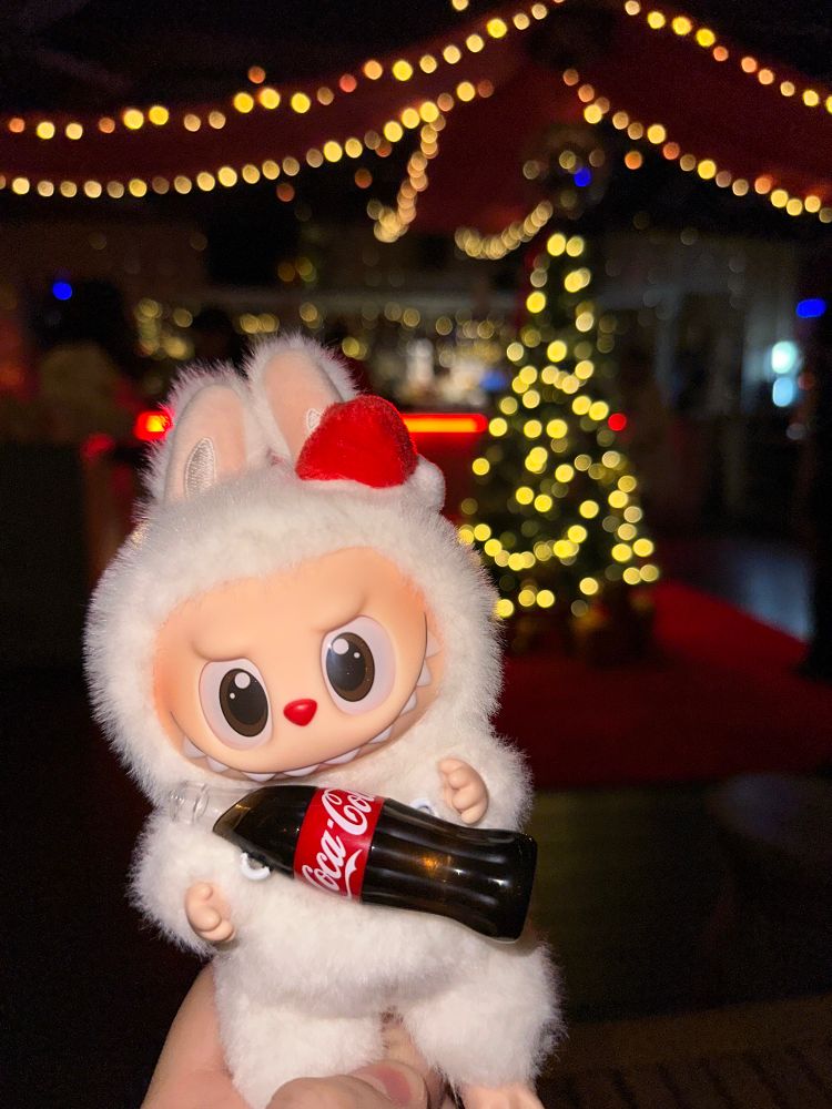Xmas labubu in front of a Christmas tree. The flash is ON.