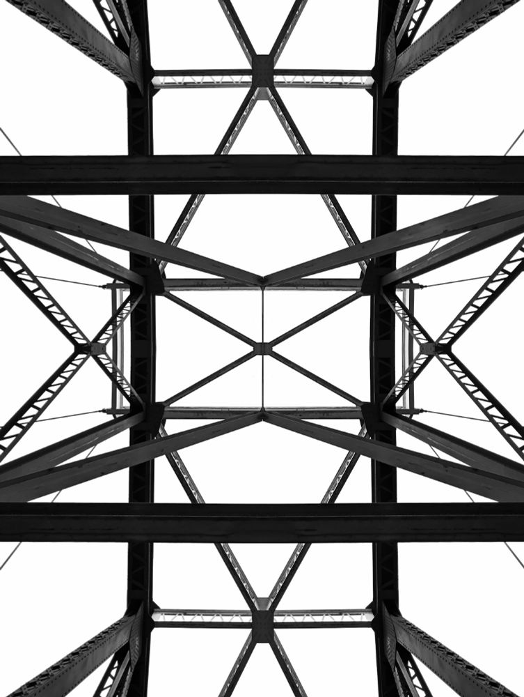 A black and white photo looking up at a perfectly symmetrical bridge.