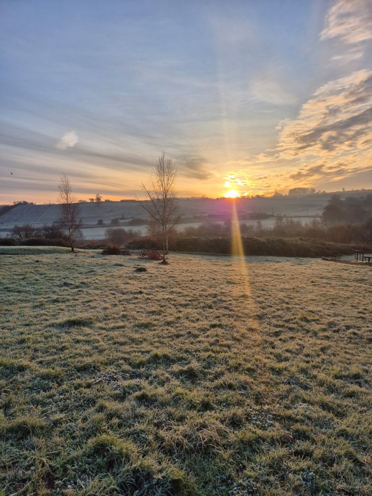 Frosty sunrise over the fields with lens flare on the sun