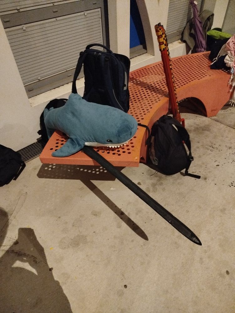 Un vanc orange entouré de sac. Dessus, Miette est posée avec sous la nageoire droite une épée médiévale en mousse abîmée 