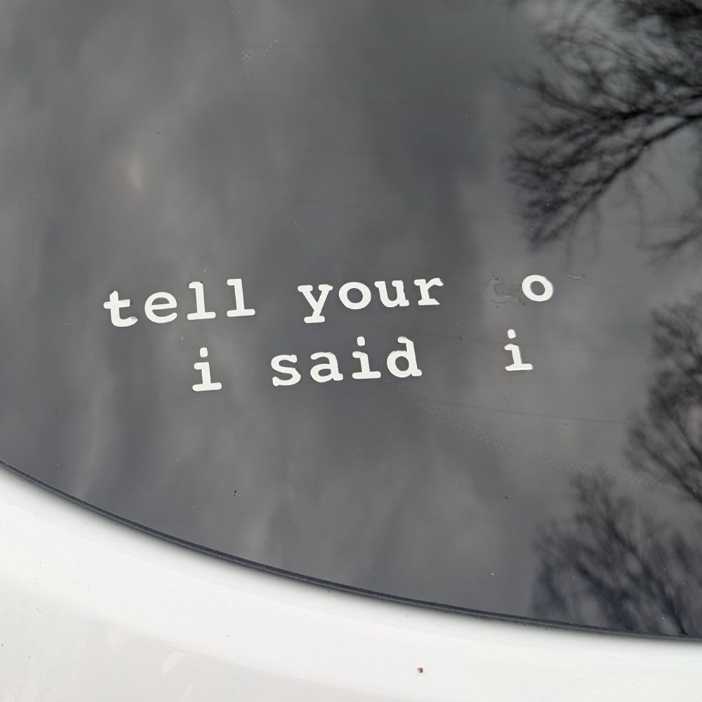 Picture of a sticker on a car window that says "tell your o i said i"