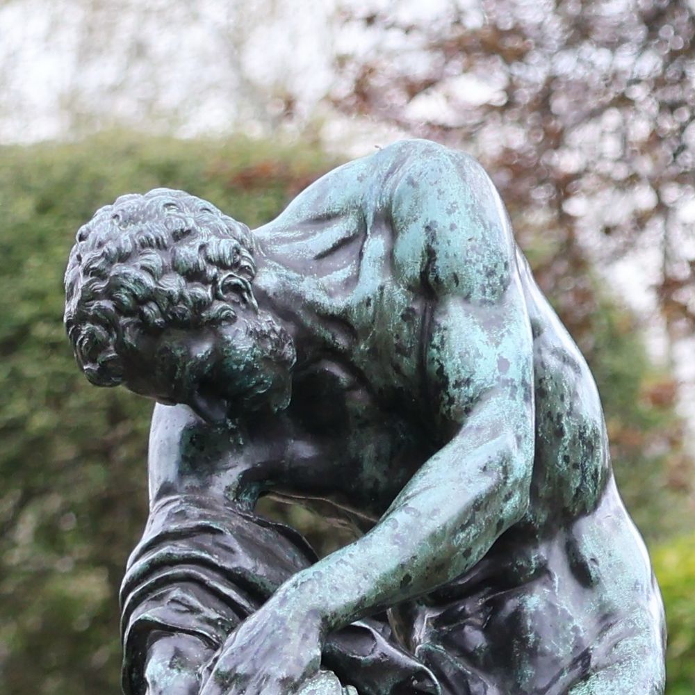 Sculpture of Milos of Croton in the Dutch Garden, Holland Park. With the photo cropped tight on his head and torso, he appears to be struggling with his drapery. 