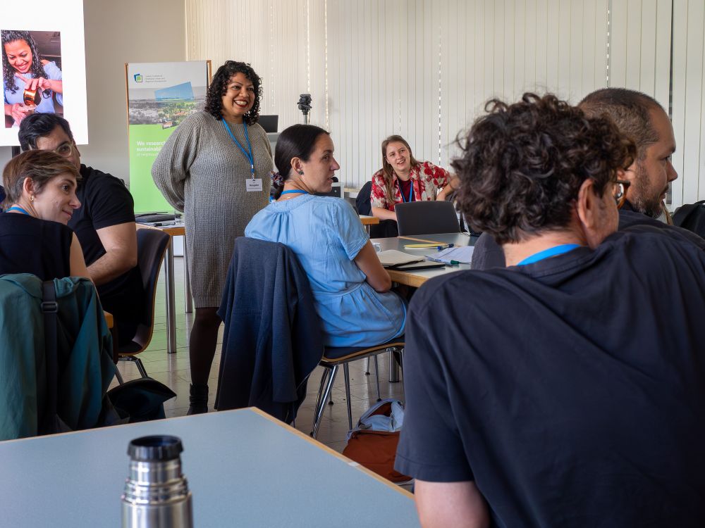 Dr. Neha Mungekar in the session on Contextualizing Justice through a #decolonial perspective. People sitting on different tables and talk to each other. 