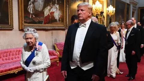 Donald Trump lumbers along next to Queen Elizabeth wearing an ill-fitting suit, doesn't blend into the crowd, fingers to short, voice too grating.