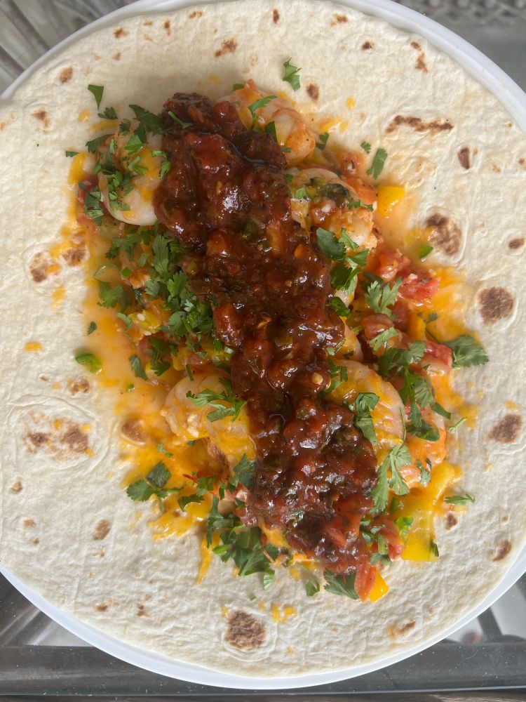 A shrimp burrito with cilantro and a homemade salsa