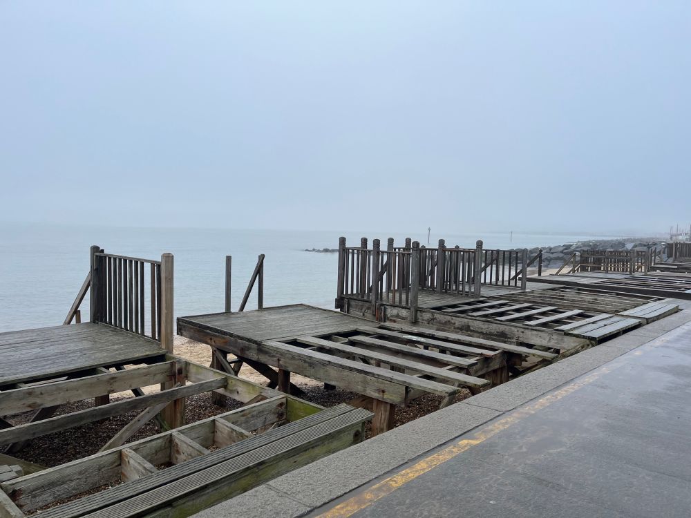 Wooden piles without the beach huts (removed for winter). North Sea, groynes in background. 