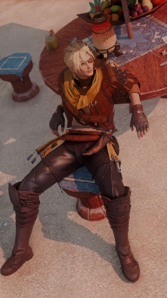 A screenshot of Riol reclining in a very casual manner at a table on the beach side. He's leaning back with his elbows propped up on the table behind him. He's also manspreading. Which is... Nice. 