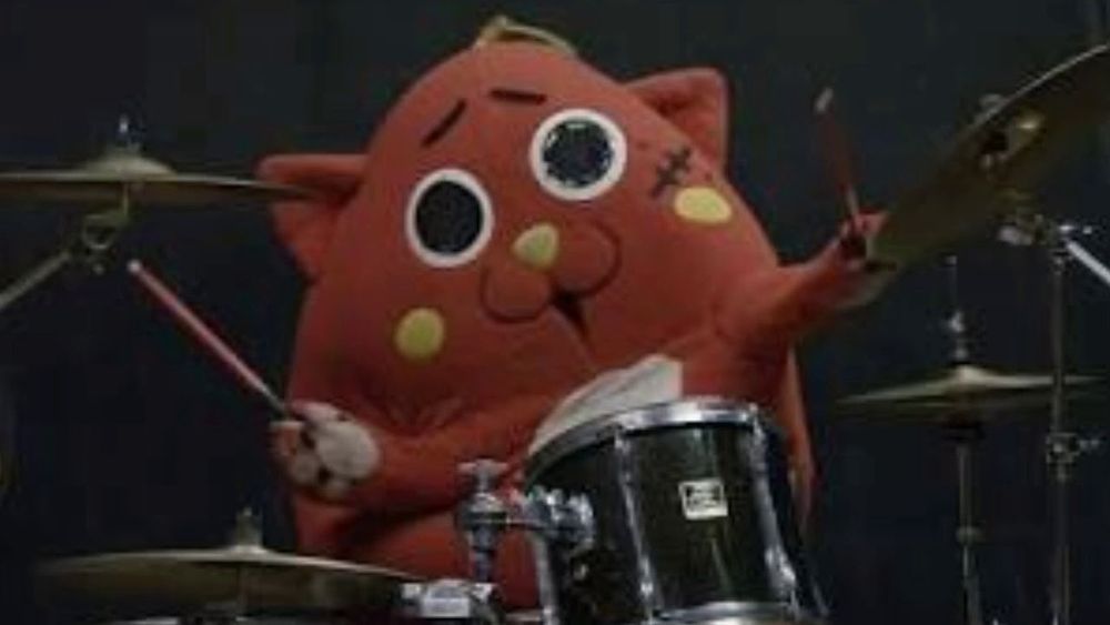 A photo of Nyango Star in costume behind a drum kit