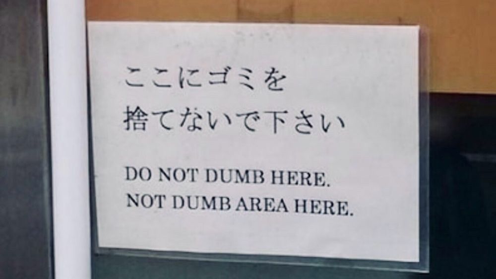 Sign on a window that reads "Do not dumb here. Not dumb area here." in both Japanese and English. 