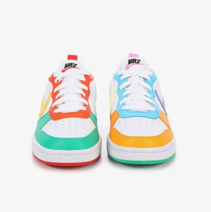 Pic of multi-colored kids' Nike low dunks. The right shoe is mainly white with orange, jade green, and yellow details and a red sole. The left shoe is also mainly white with light blue, light orange, purple, pink, and lemon yellow details with a green sole.