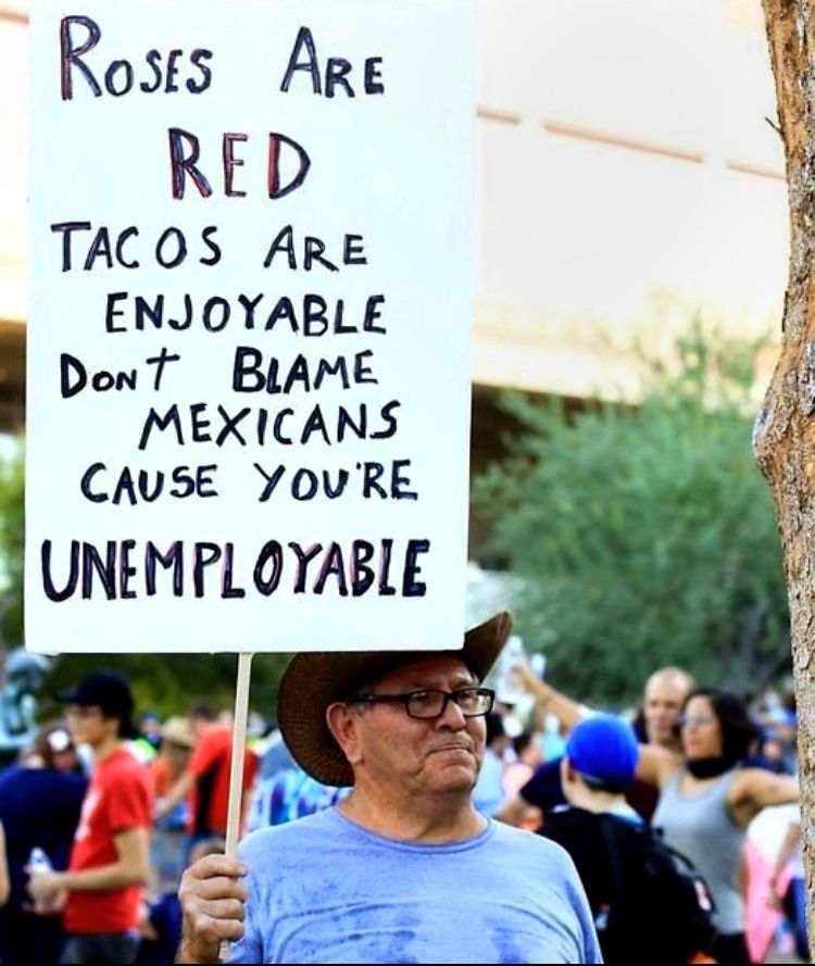 Middle-aged guy wearing glasses and a cowboy hat while standing in a crowd. He is holding a sign that says:
Roses are red
Tacos are enjoyable
Don’t blame Mexicans because you’re unemployable