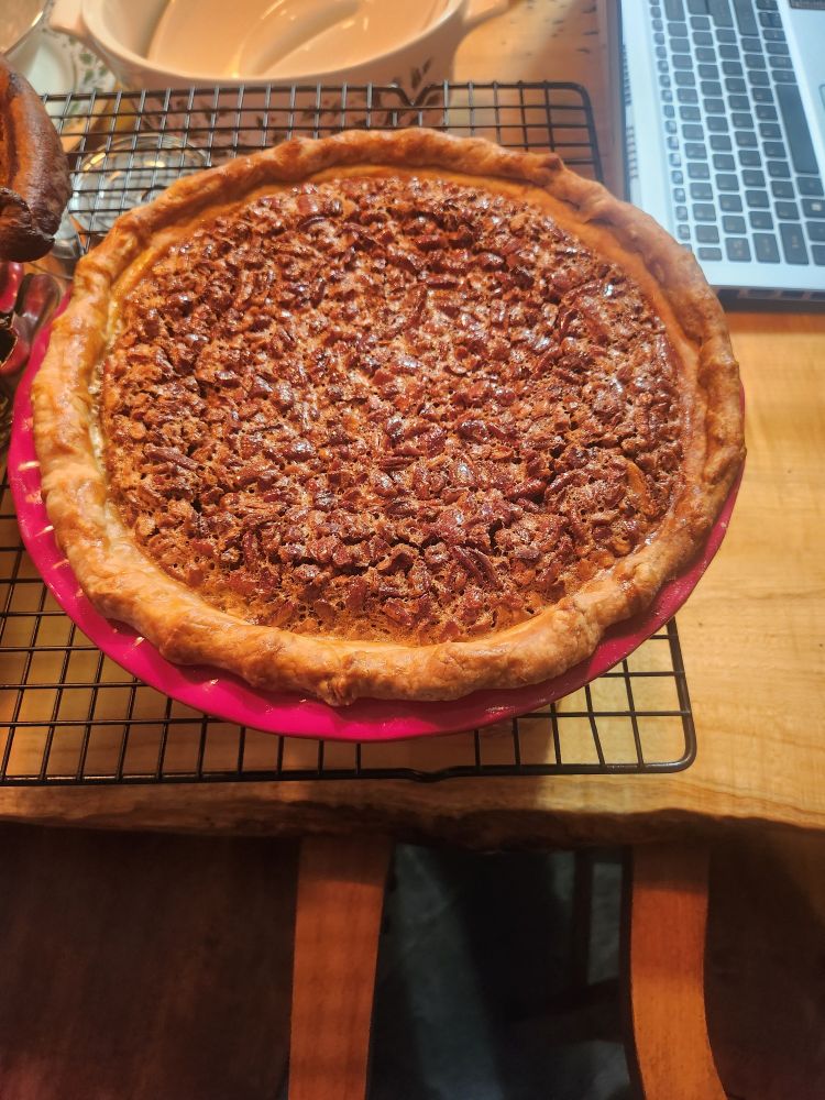 A pecan pie on a cooling rack. The crust looks perfect.