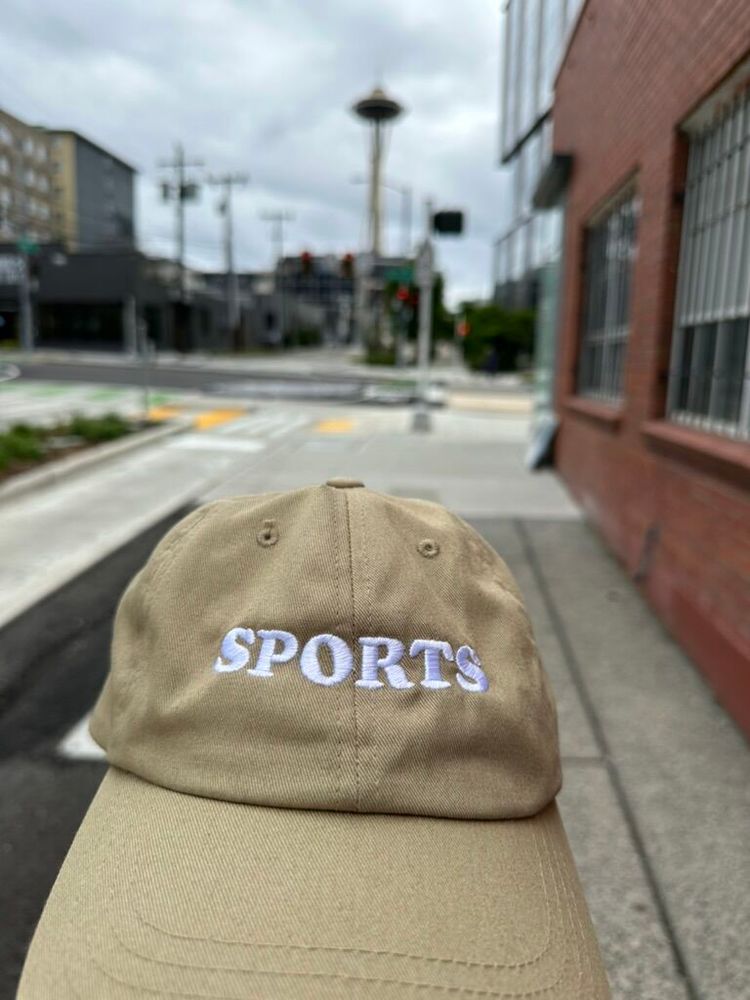 A tan baseball cap that reads SPORTS in white embroidery. It looks great #shirtgood 
