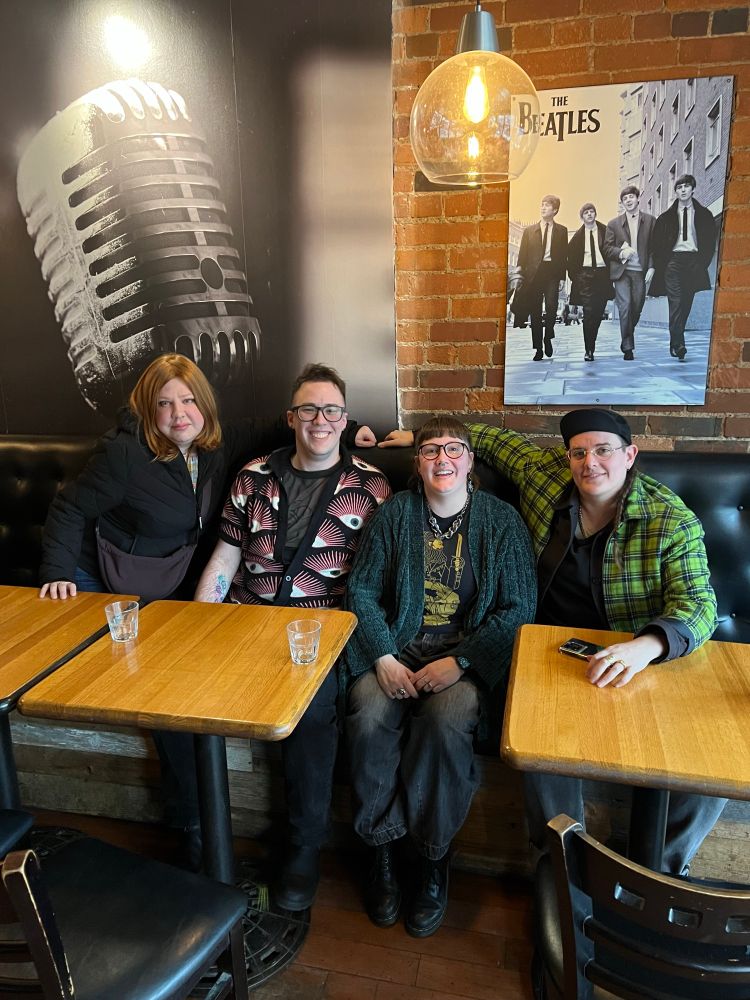 Andrea, Owen, me, and Roxi sitting along the back booth at a restaurant and smiling at the camera. 