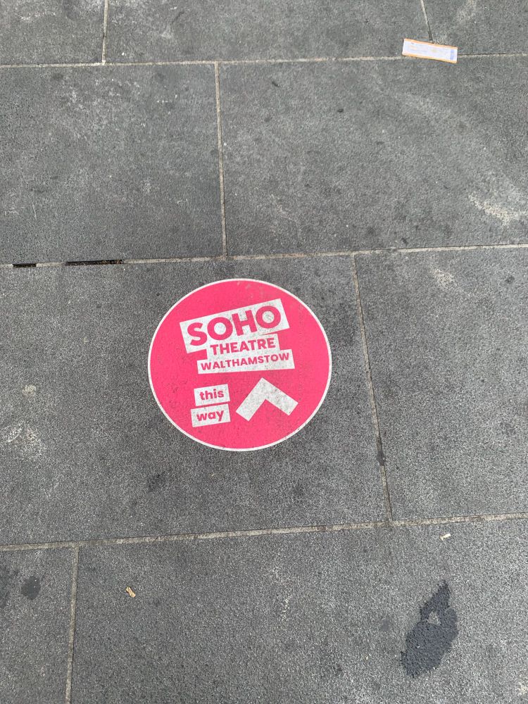 A cheerful pink circular sticker on the pavement directing me to the Soho Theatre Walthamstow.  