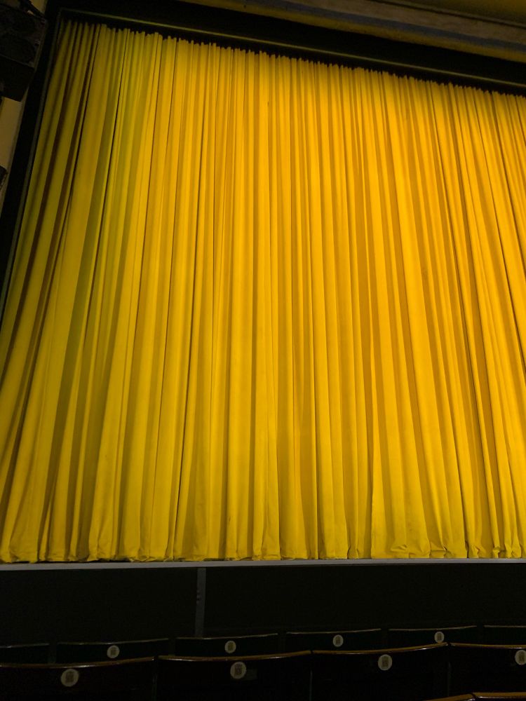 The distinctive yellow curtain covering the stage of the Fortune Theatre. When it opens, Operation Mincemeat will happen. The photo shows a very nice view from the stalls, on the correct side to cry at Dear Bill.