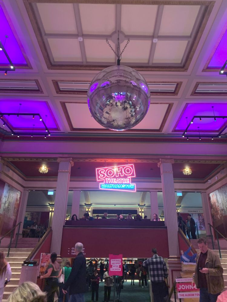 A large, I want to say Art Deco but I don’t know, foyer with a huge mirrorball and a snazzy neon sign saying “Soho Theatre Walthamstow”